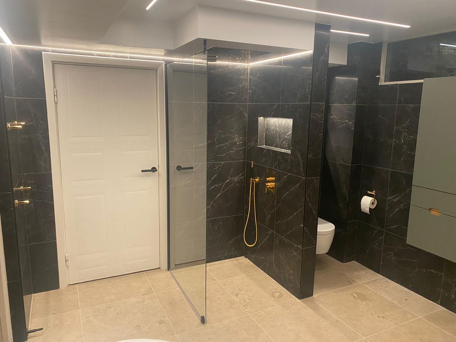 Modern black marble bathroom with glass shower and gold fixtures