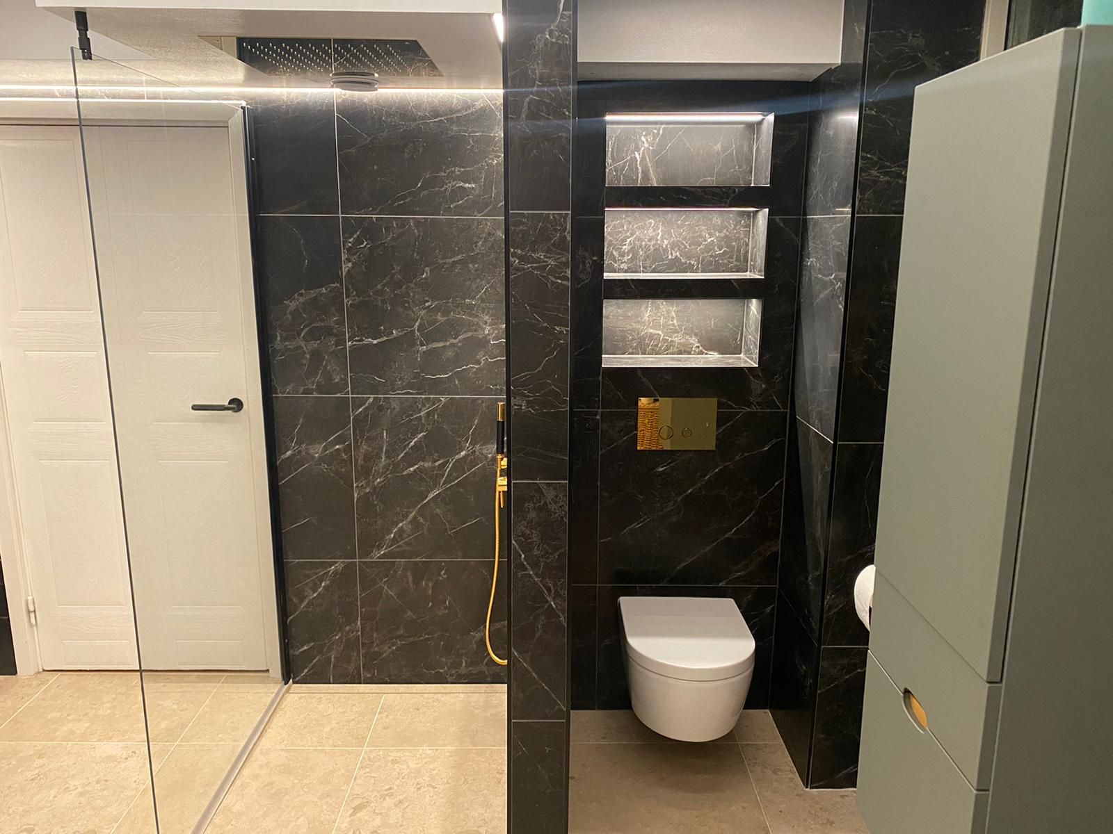 Black marble bathroom with wall-mounted toilet and tile niches