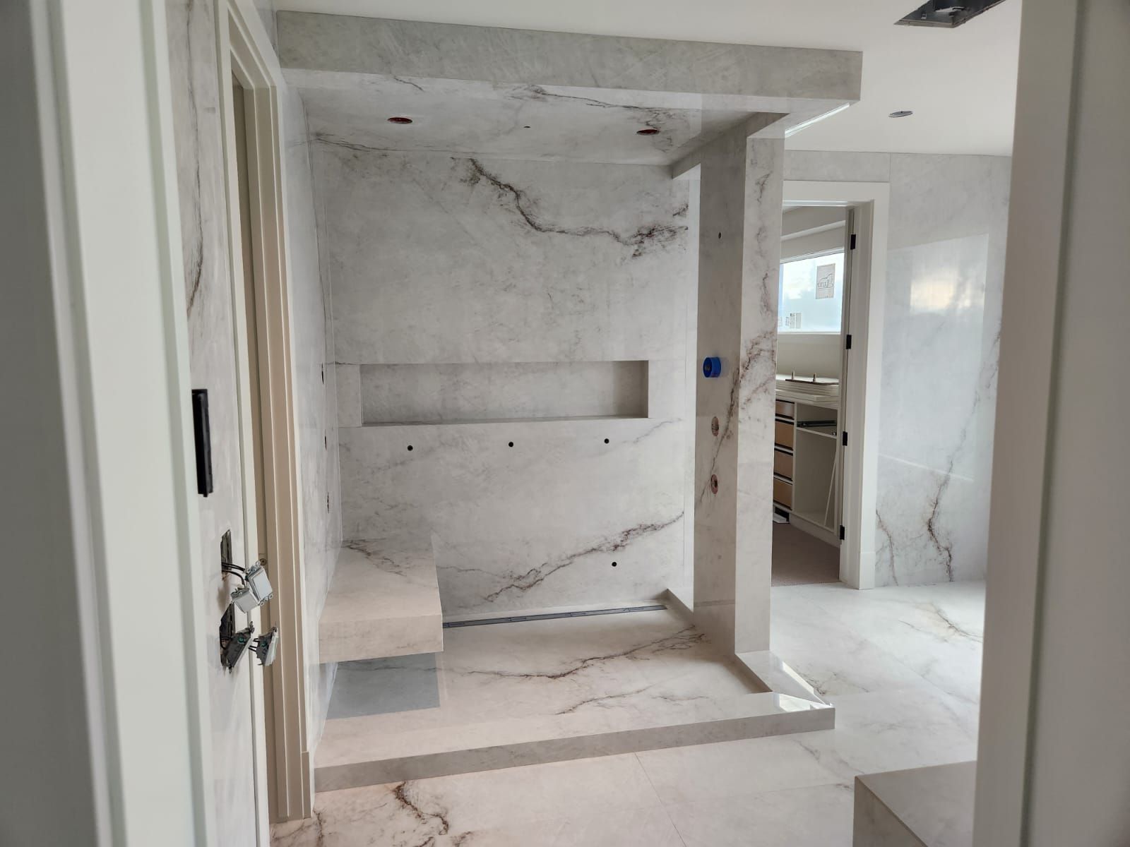 White marble walk-in shower with bench and niche