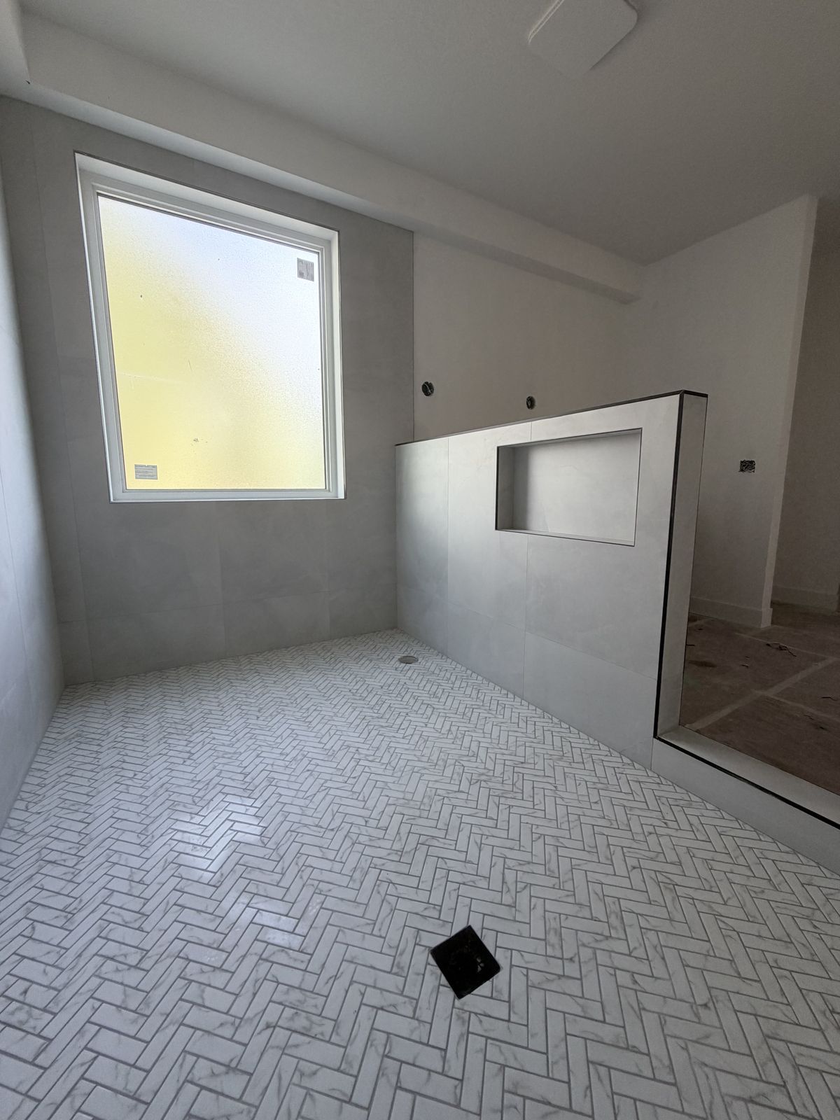 Gray tile bathroom with tile niche and herringbone floor